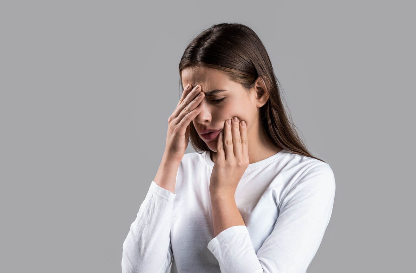 Person holding their cheek and forehead showing discomfort from a headache potentially linked to toothache pain